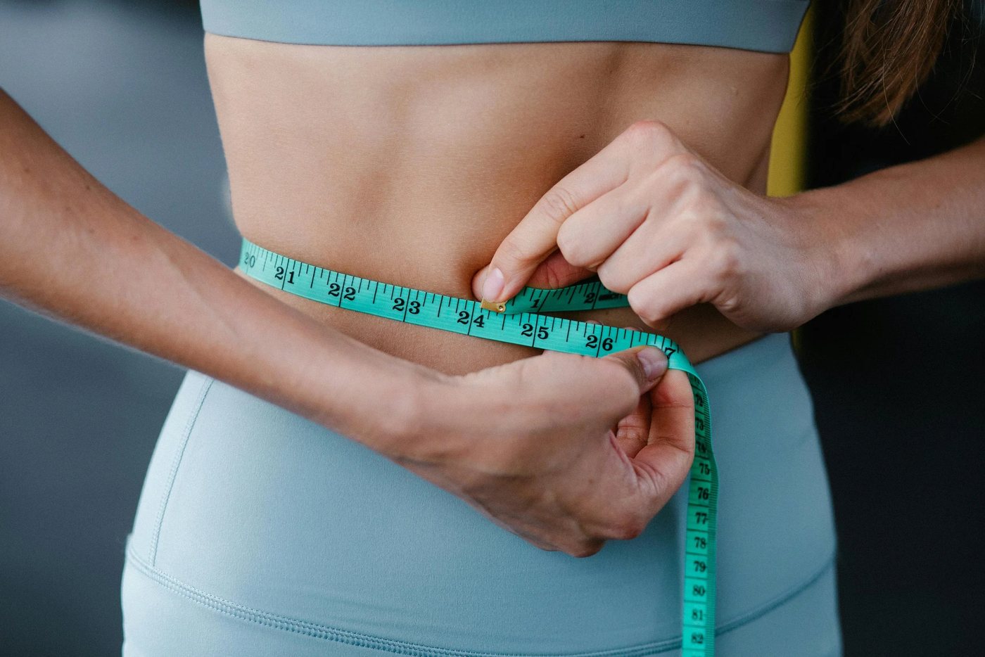 Close-up of a woman measuring her waist with a tape measure during a medically supervised GLP-1 weight loss program at The Aesthetic Ranch in Fort Lauderdale, FL.